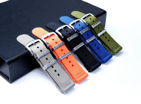 Array of colorful two-piece NATO straps displayed with a sleek black presentation box on a white background - Under the Cuff exclusive collection.